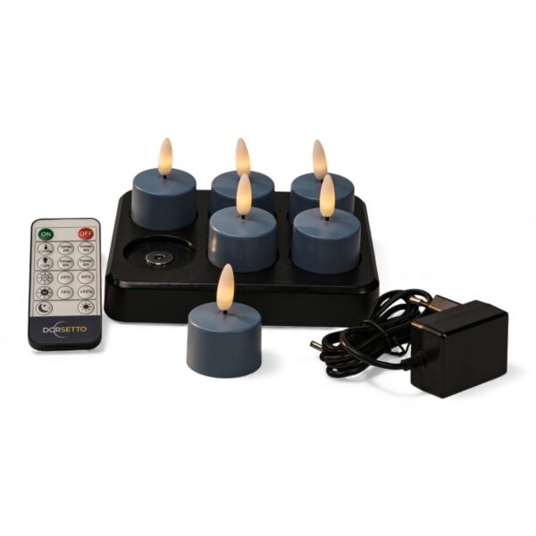 Home 24 Ein Set aus sechs blauen LED-Teelichtern mit flammenförmigen Spitzen, die auf einer schwarzen Ladestation angeordnet sind, zusammen mit einer Fernbedienung und einem schwarzen Netzadapter.