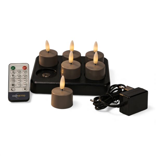 Sechs batteriebetriebene LED-Teelichter mit realistischen Flammen auf einer schwarzen Ladestation, zusammen mit einer Fernbedienung und einem Netzadapter mit Kabel, angeordnet auf einem weißen Hintergrund.